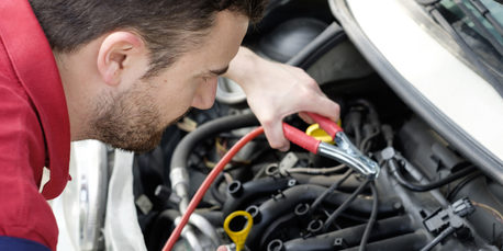 mechanic working on car engine with electricity cables